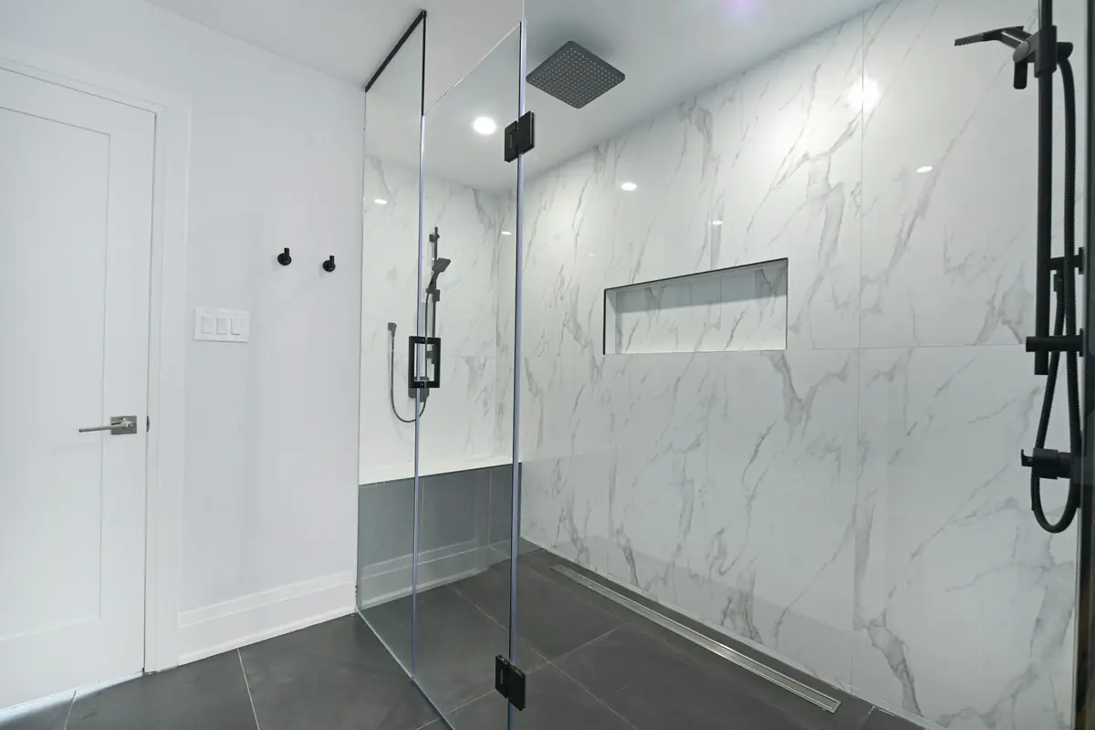Walk-in shower with frameless glass and white marble-look tile